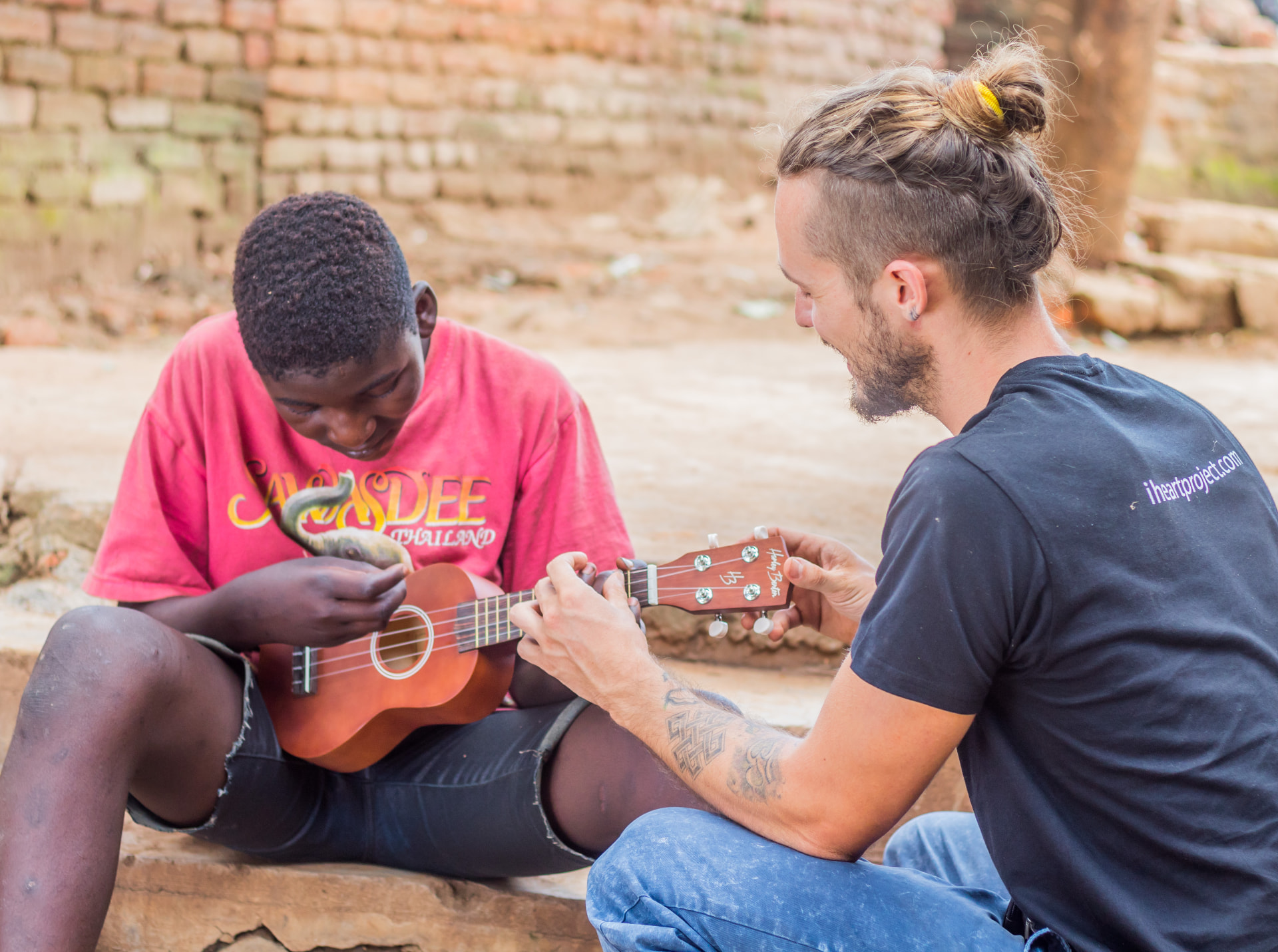A team member showing a young person how to play the ukulele